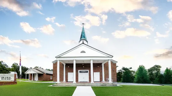 The Sauldam Baptist Church sanctuary: red brick, white columns, and a white steeple.