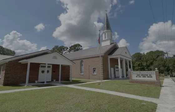 A side view of the Sauldam Baptist Church building and its covered brick portico entrance.